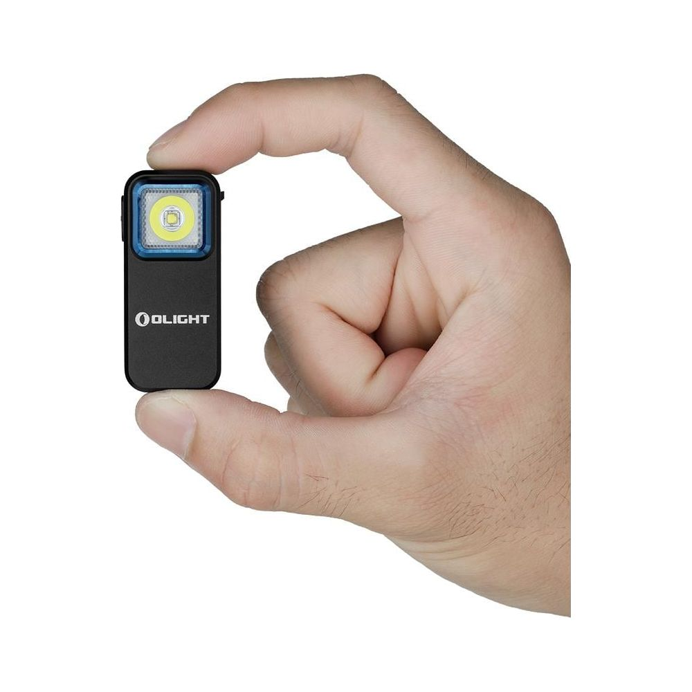Una mano tiene una piccola torcia Olight nera con LED acceso.