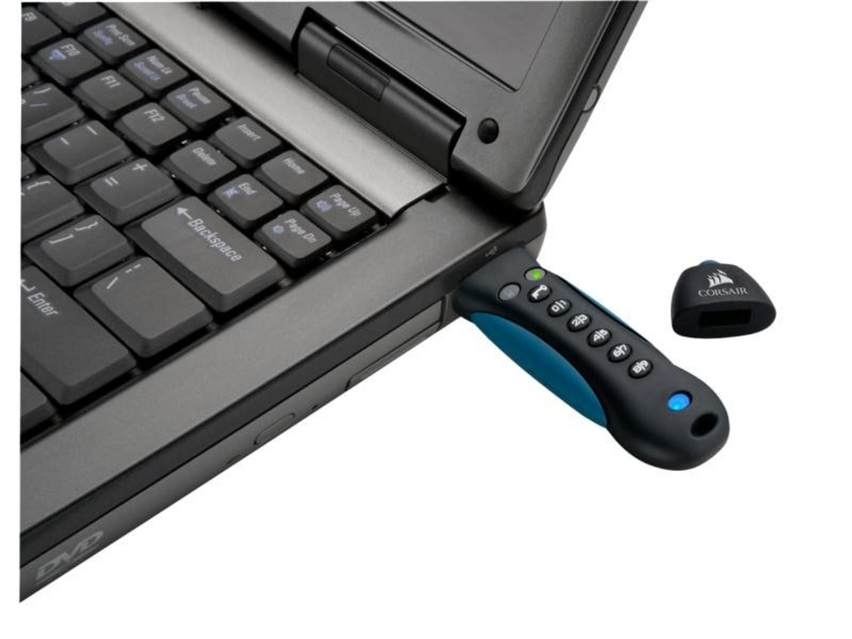 Pendrive marki Corsair podłączony do laptopa. Obok leży nasadka.