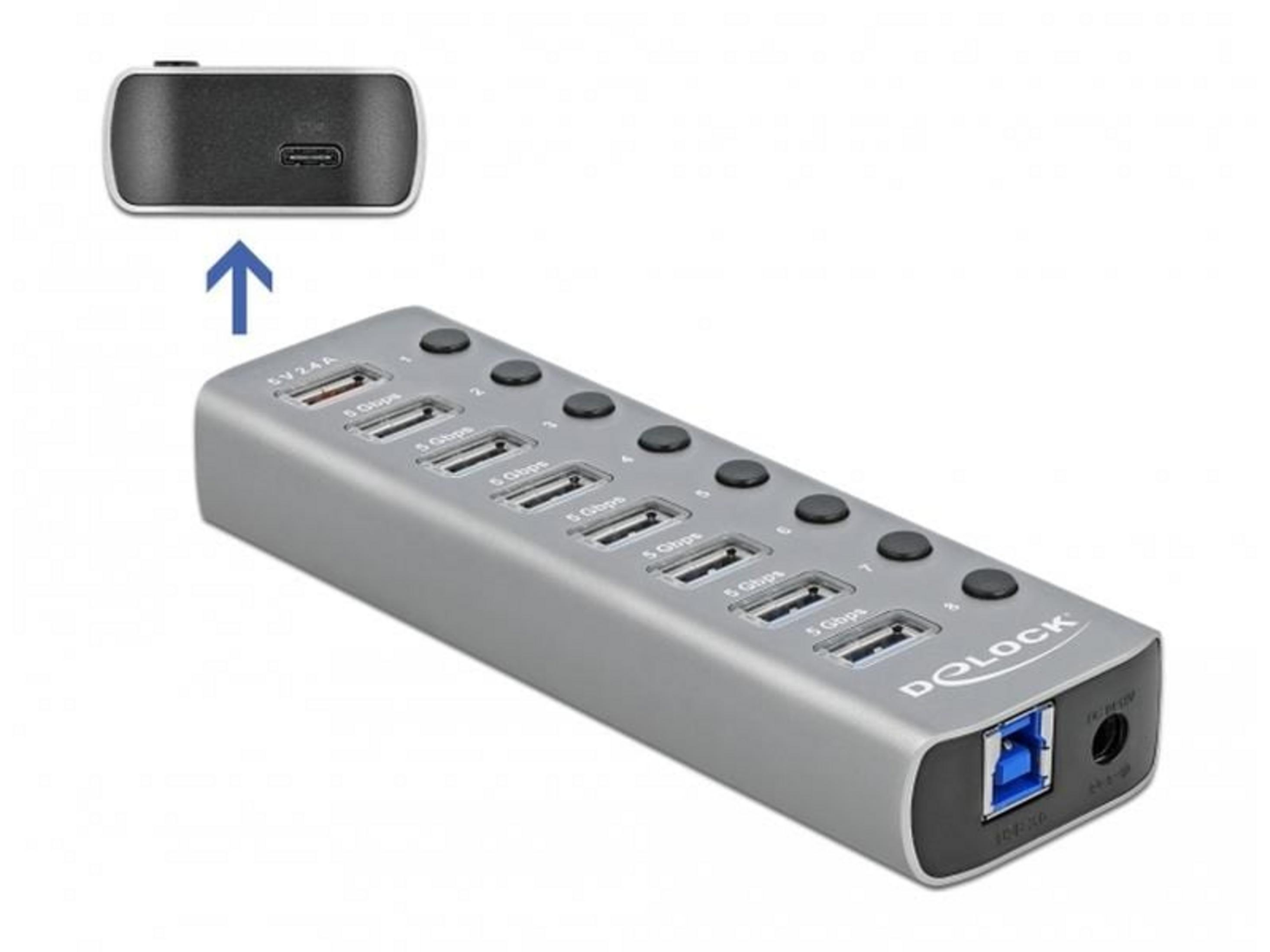 Grauer USB-Hub mit 8 Anschlüssen und Netzteilanschluss. Oben ein kleiner schwarzer Adapter.