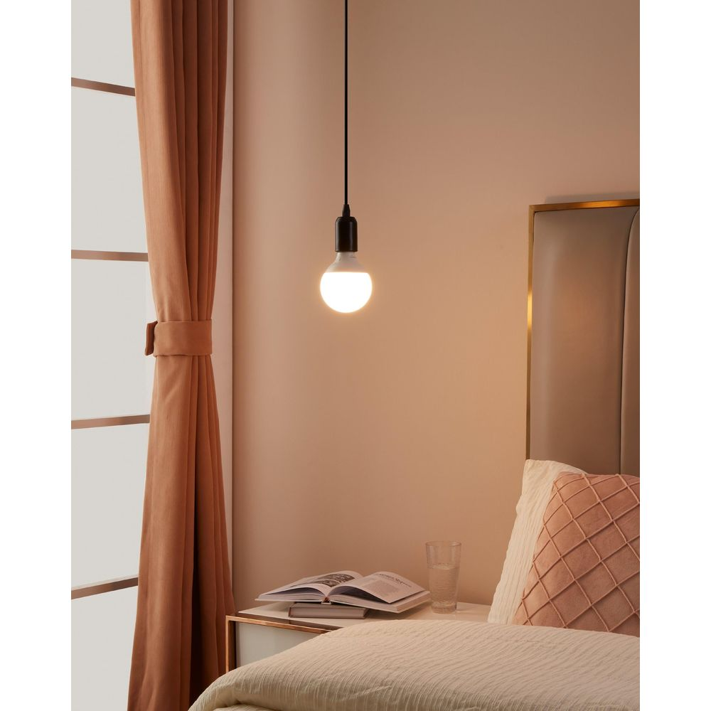 Una mesita de noche con libro y vaso de agua junto a una cama.