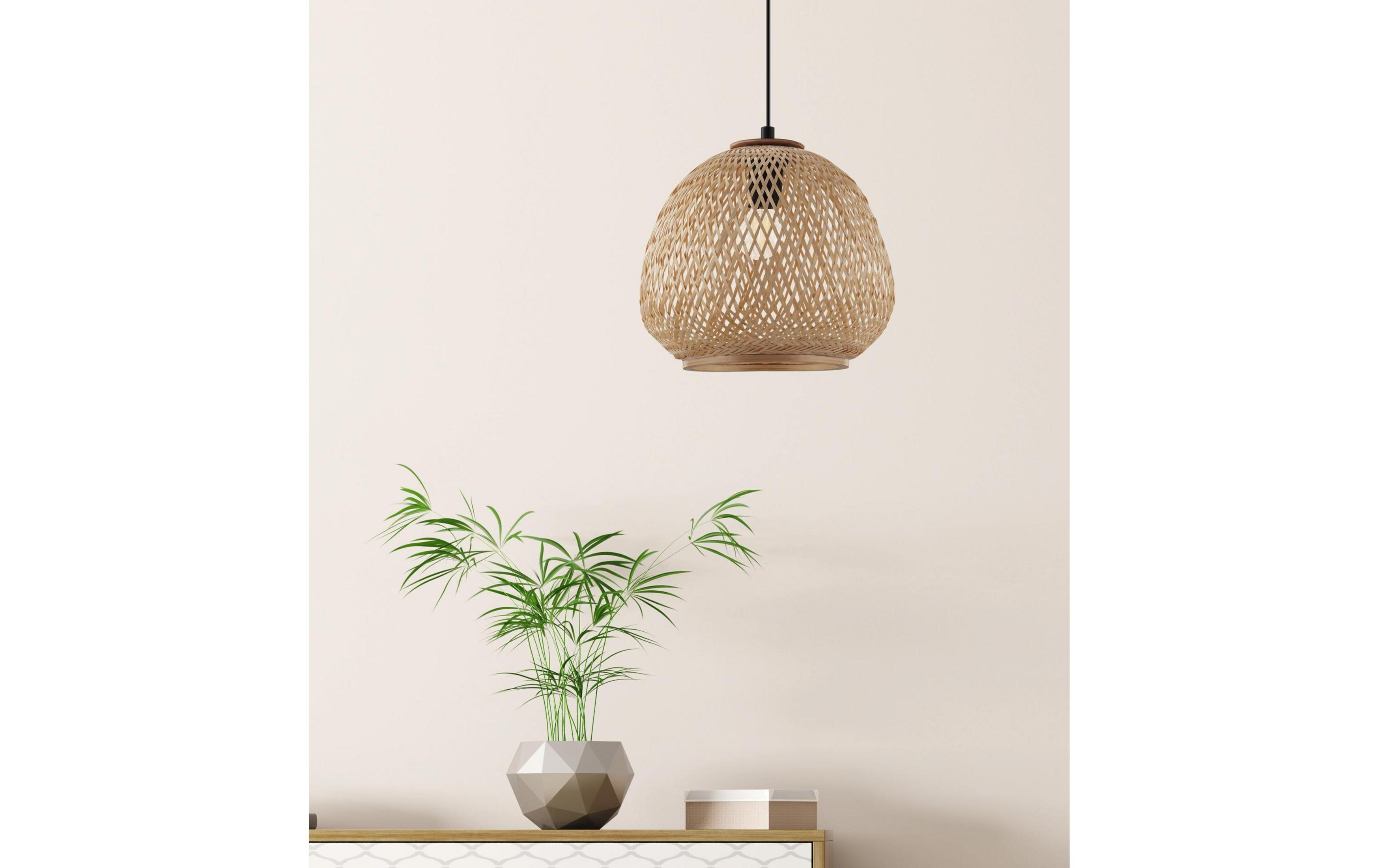 Lampada a sospensione intrecciata sopra un vaso con piante verdi su una superficie.