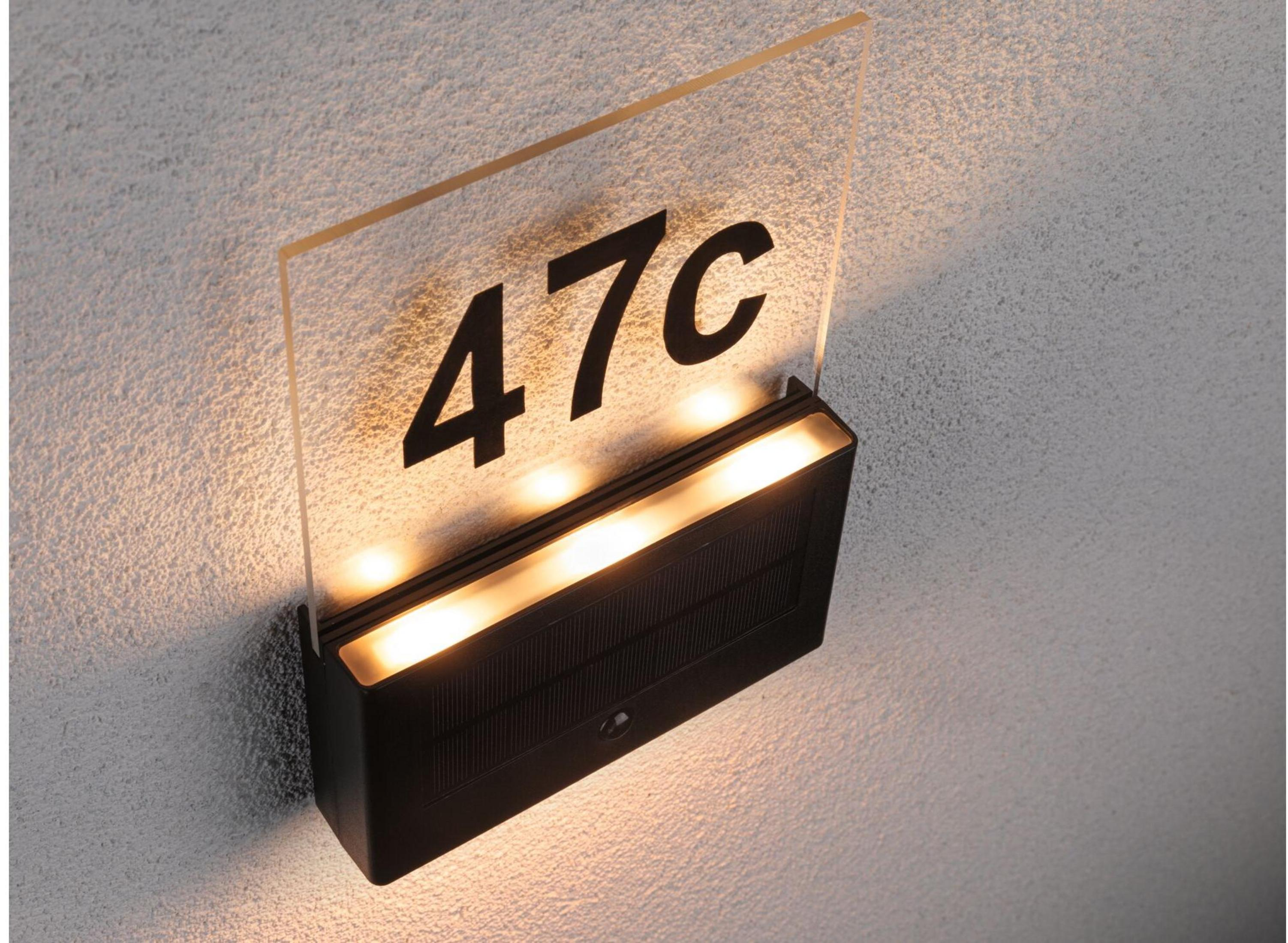Eine beleuchtete Hausnummer 47c aus Glas mit schwarzer Schrift an einer Wand.