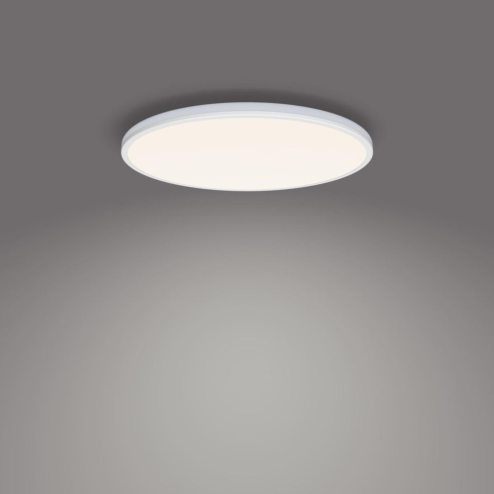 Una lampada da soffitto rotonda bianca con luce diffusa su sfondo grigio.