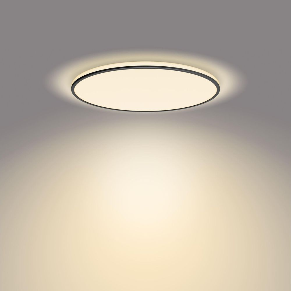Una lampada da soffitto rotonda e luminosa con bordo nero brilla verso il basso.