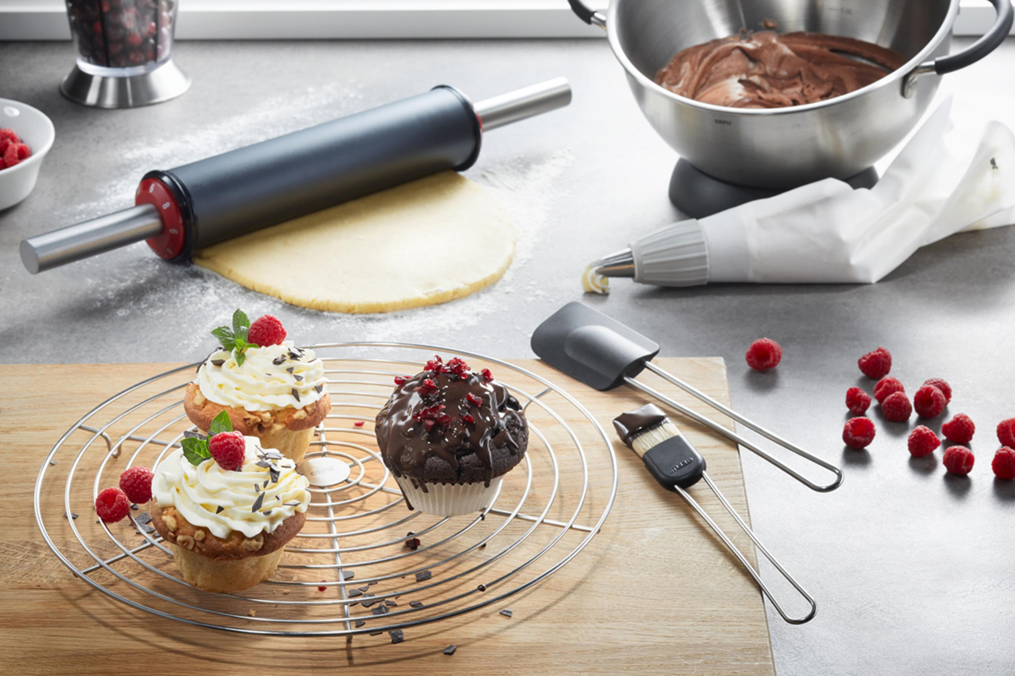 Kuchen und Backutensilien mit Himbeeren und Schokolade auf Arbeitsplatte.
