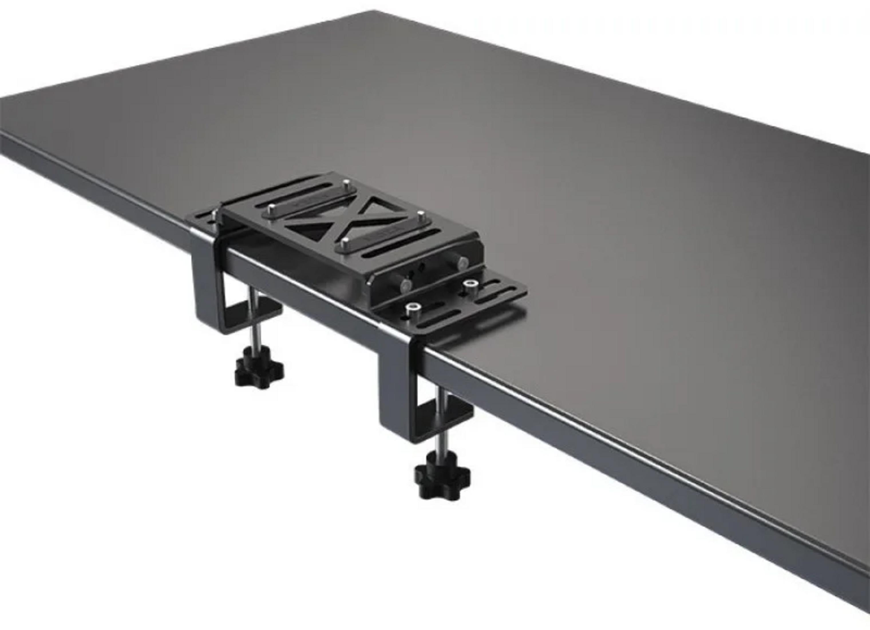 Un adaptateur de fixation de bureau noir avec des pinces sur un plateau sombre.