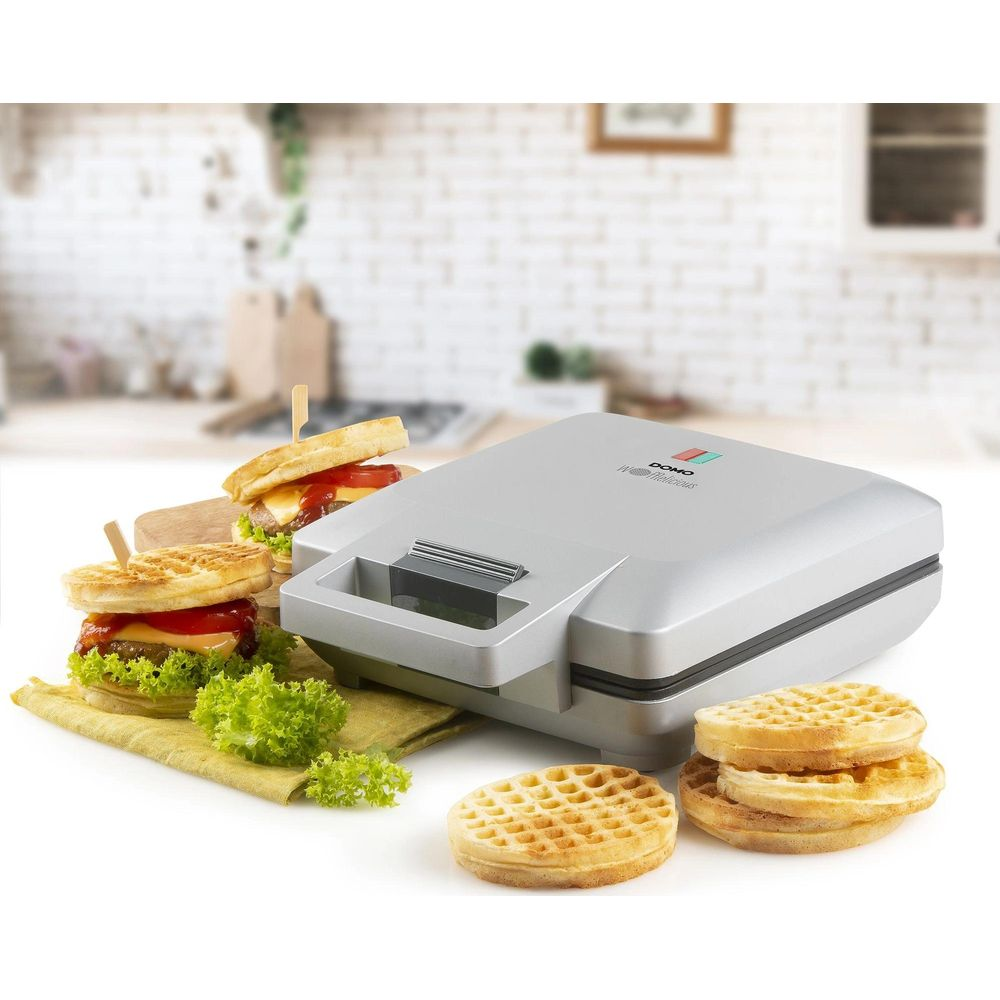 Ein silberner Waffelautomat mit Burgern und Waffeln daneben.