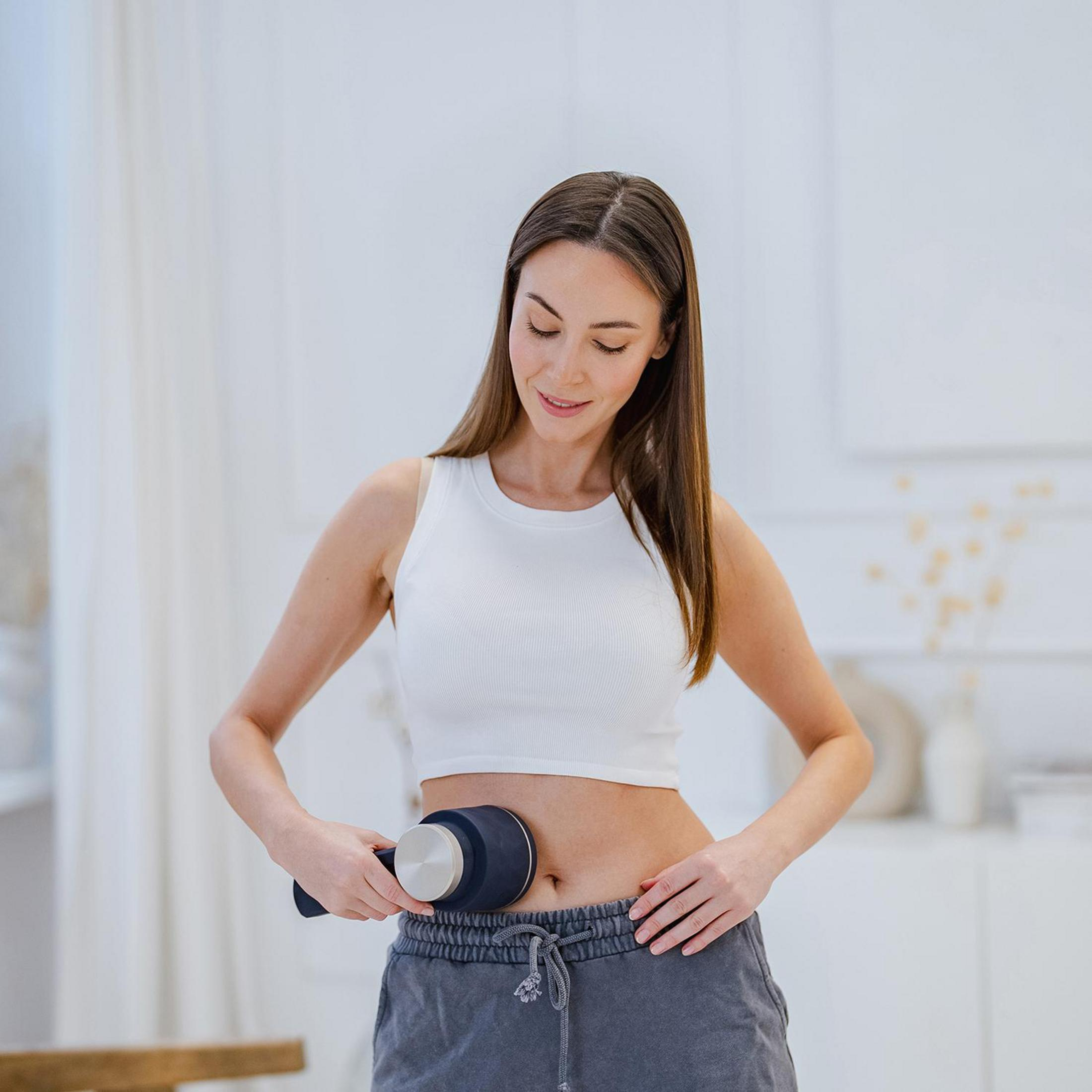 Eine Frau mit einem Schlankheitsapparat in der Hand, der auf ihren Bauch gerichtet ist.