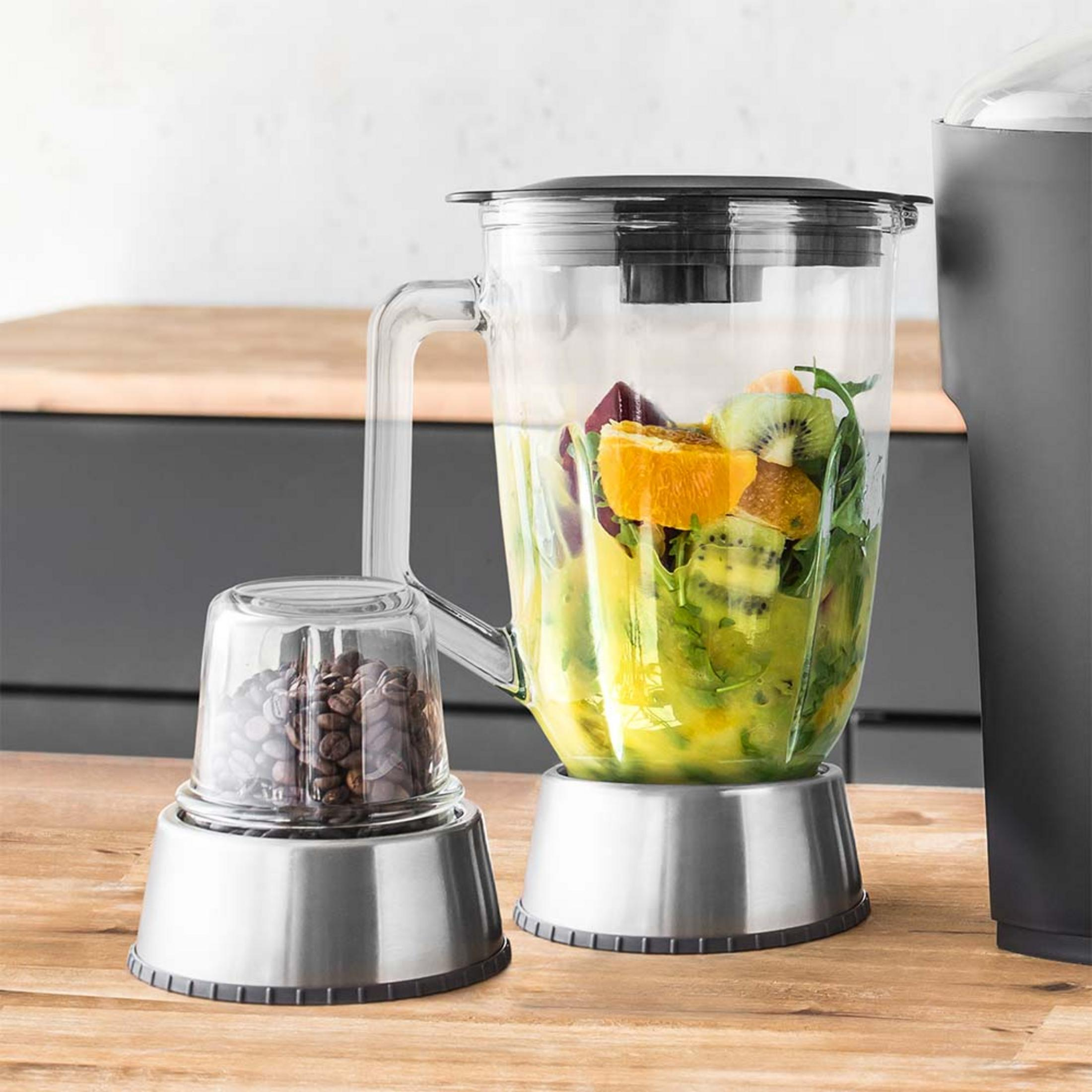 Ein Mixer mit Früchten und ein kleiner Behälter mit Kaffeebohnen.