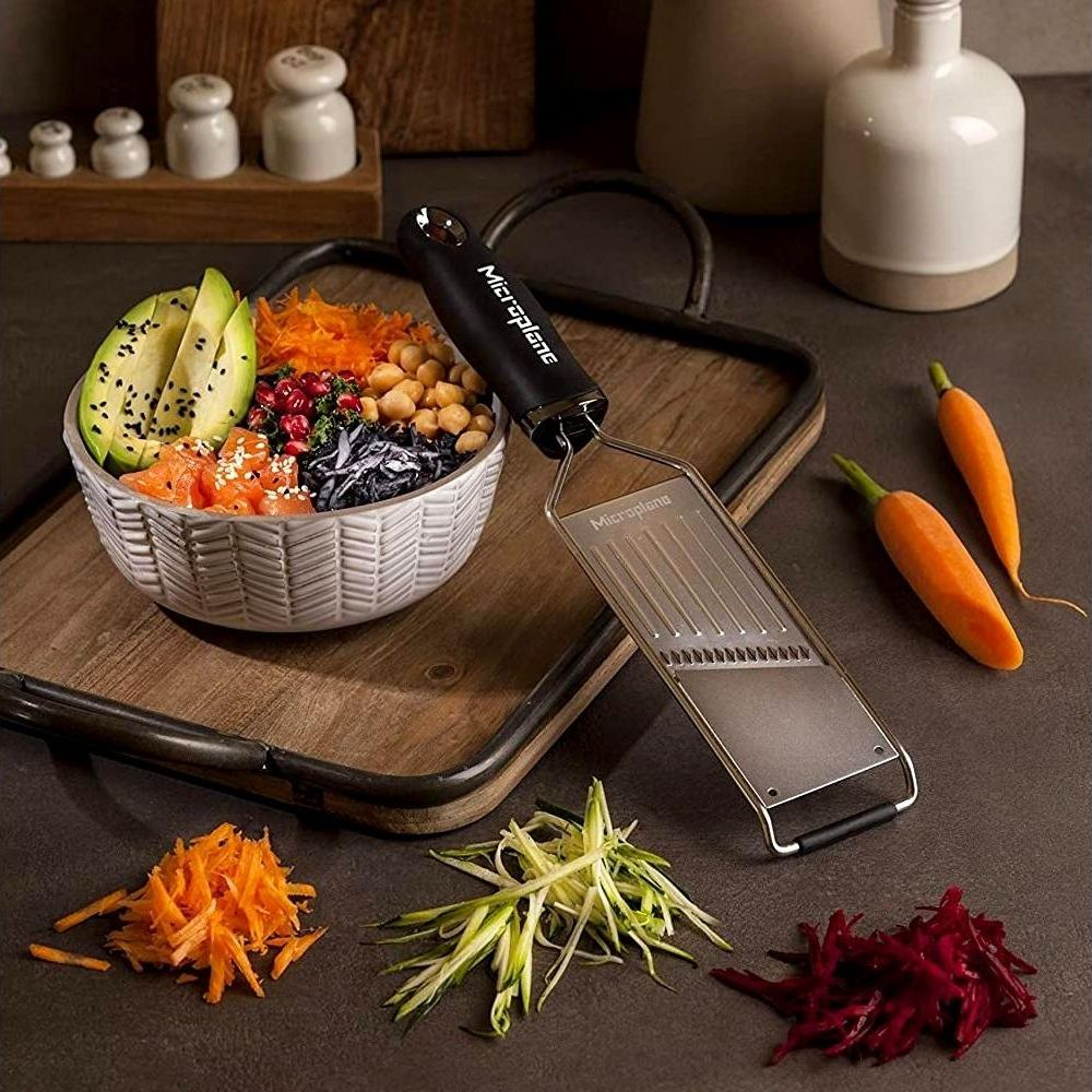 Eine Schüssel mit Essen, Avocado, Lachs, Kichererbsen und geriebenen Karotten. Ein Grater ist in der Nähe.