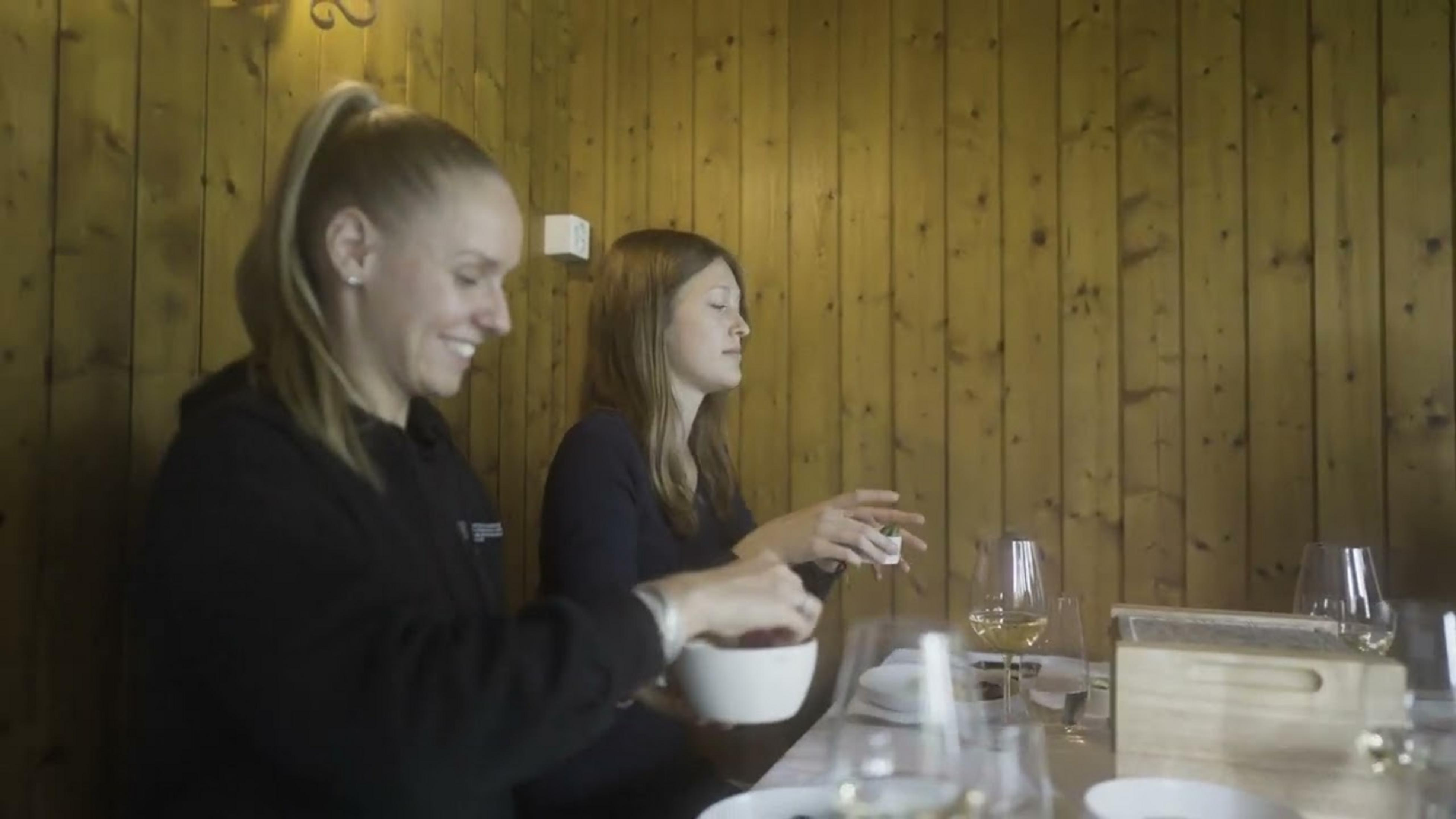 Deux femmes assises à une table en bois dans un restaurant. L'une tient un bol de baies.