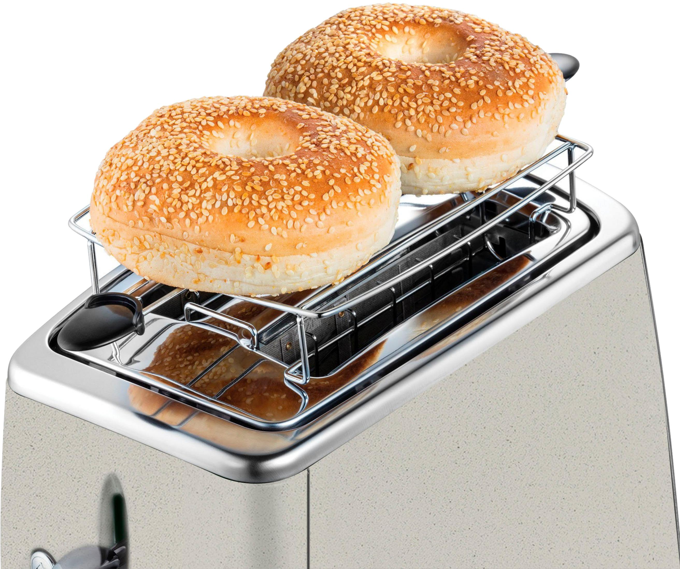 Deux bagels au sésame sur un support de grille-pain au-dessus d'un grille-pain argenté.