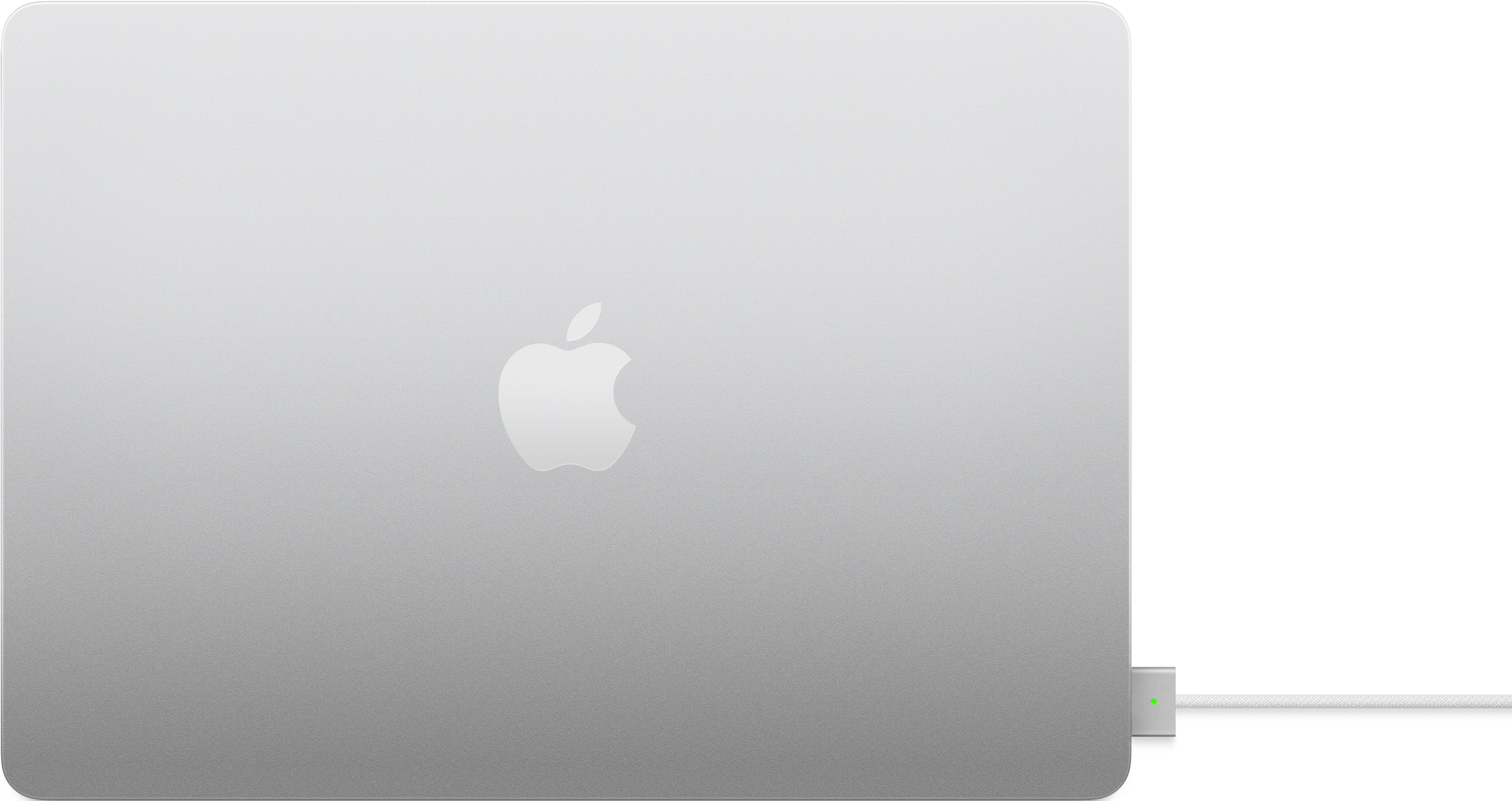 Un MacBook argentato con logo Apple illuminato, collegato a un cavo di ricarica.