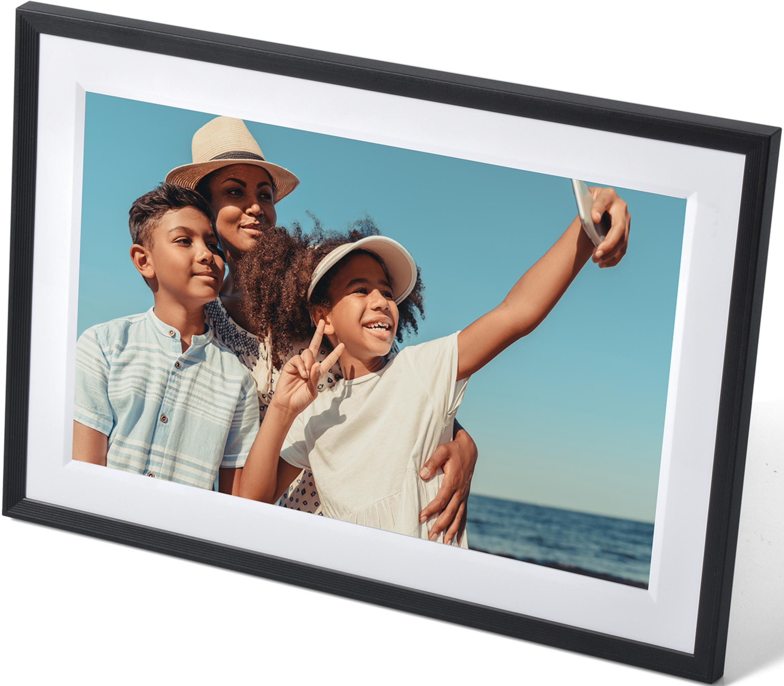 Familia en la playa tomándose una selfie con cielo azul y mar.