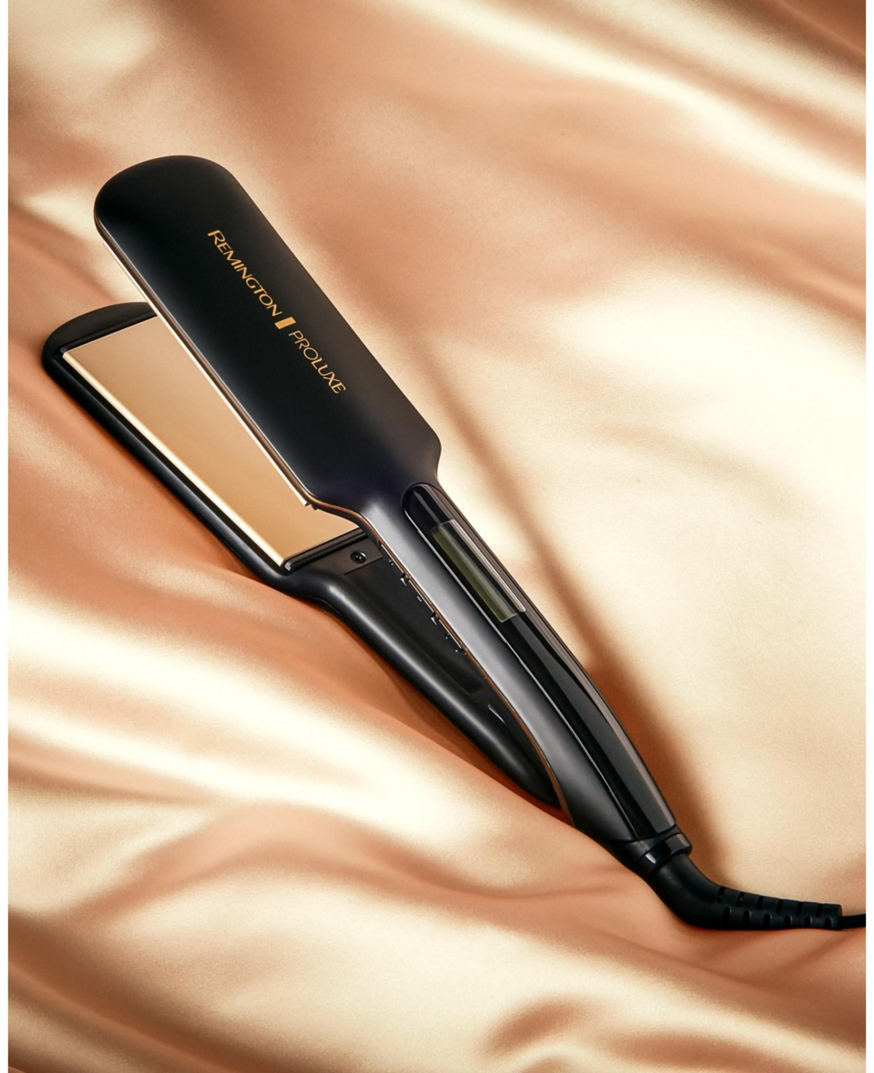 Czarna prostownica Remington ze złotymi płytkami na jedwabistej tkaninie.