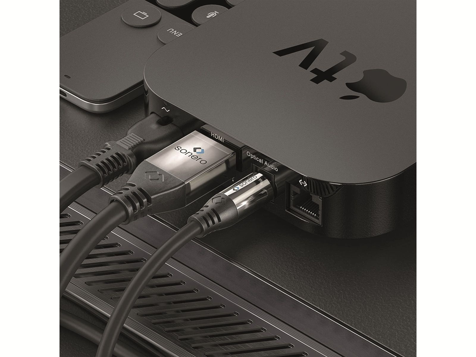 Nahaufnahme eines Apple TV-Geräts mit angeschlossenen HDMI- und optischen Audiokabeln.