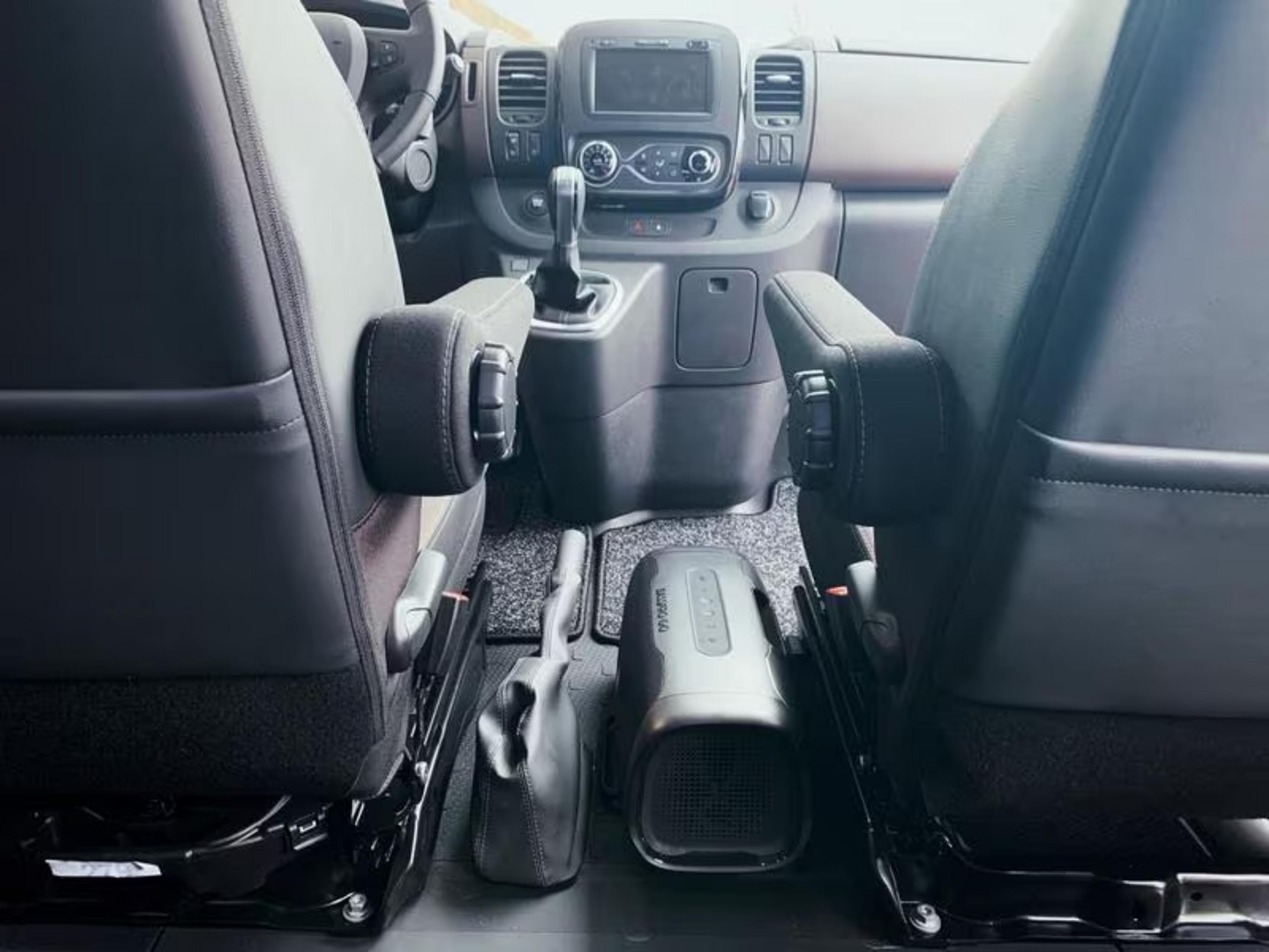 Innenraum eines Transporters mit zwei Sitzen, einem Gerät und einem Staufach.
