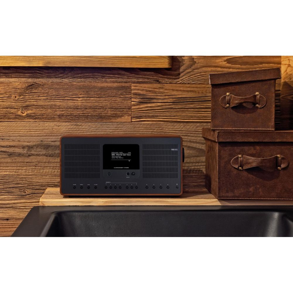 A black digital radio sits on a wooden shelf next to brown storage boxes.