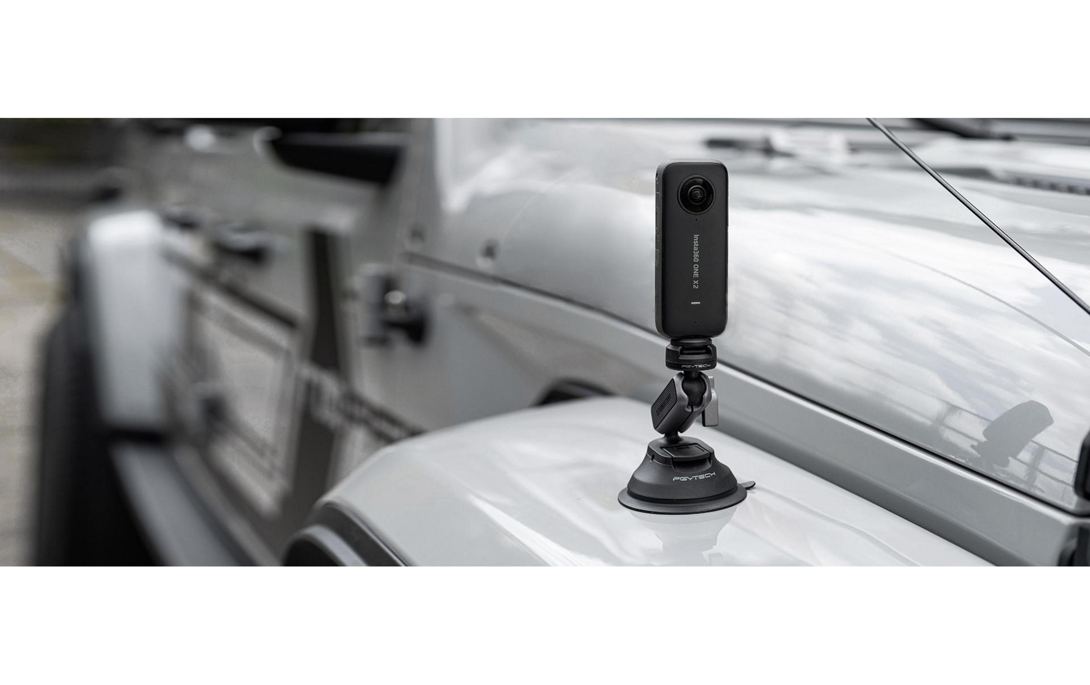 Ein schwarzer Insta360 ONE X2 auf einem Saugnapfhalter an einem weißen Jeep.