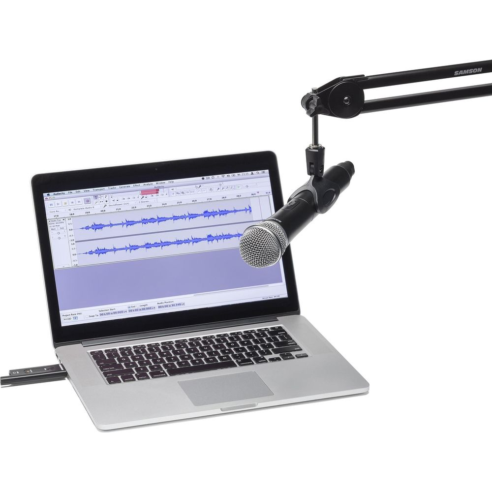 Un microfono pende sopra un laptop che visualizza il software Audacity con forme d'onda.