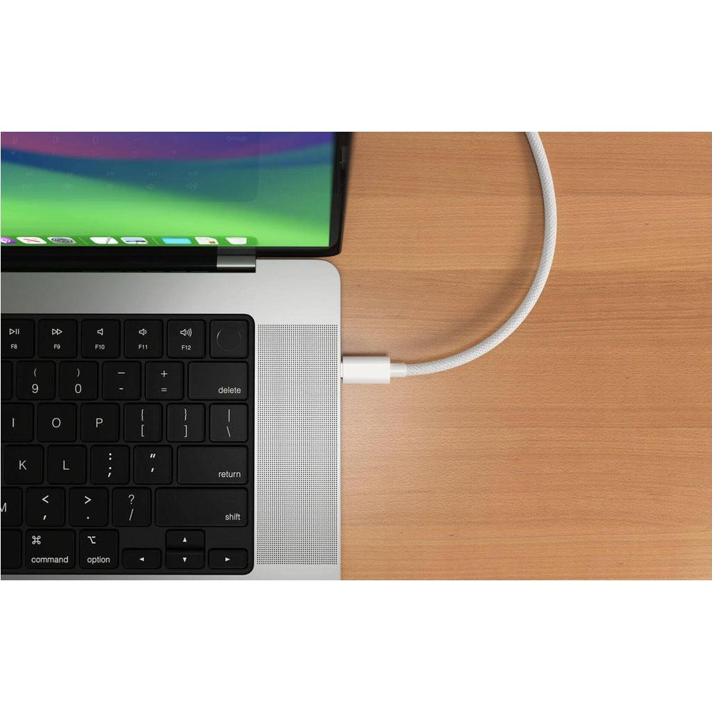 Un cavo di ricarica bianco è collegato a un laptop argentato su una scrivania di legno.