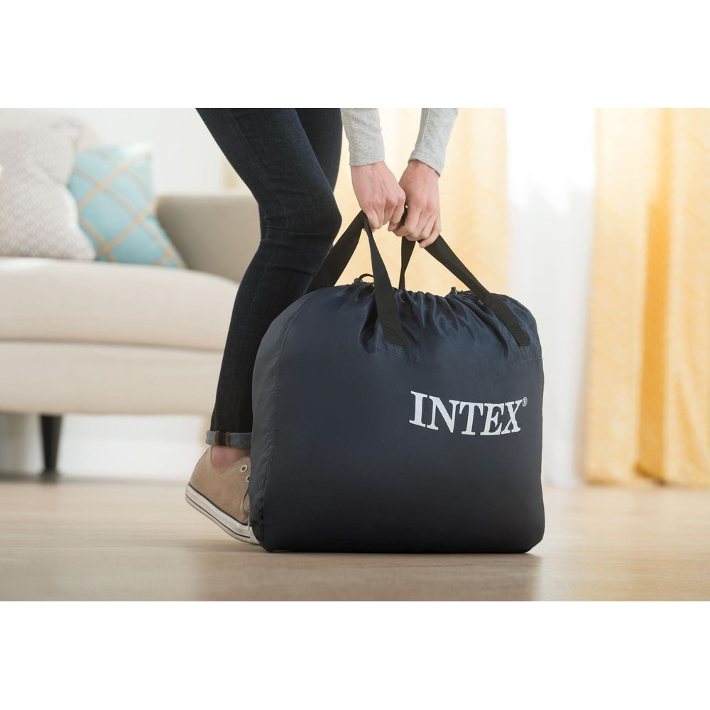 Una persona con jeans y zapatillas lleva una bolsa INTEX azul oscuro.