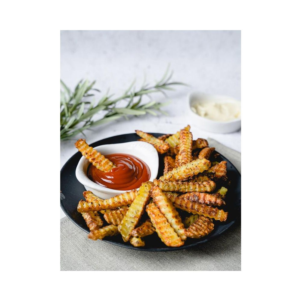 Knusprige Pommes mit Ketchup und Mayo auf schwarzem Teller, garniert mit Rosmarin.