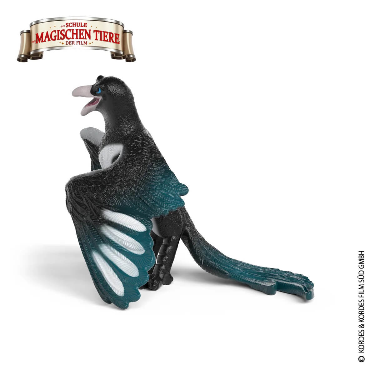 Eine kleine schwarze Figur eines Vogels mit blauen Augen, grünen Flügeln und weißer Brust.