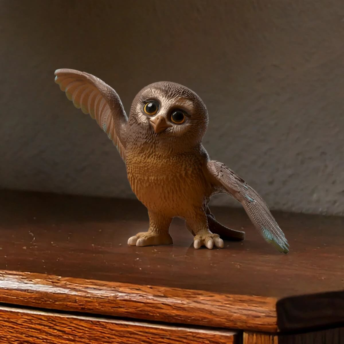 Kleine braune Eule mit großen Augen, die auf einem Holztisch steht.