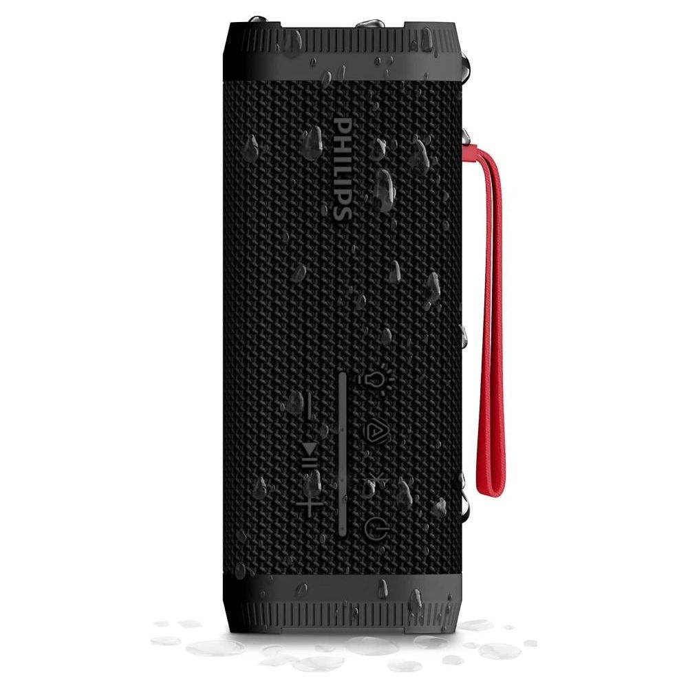Haut-parleur cylindrique noir avec sangle rouge, couvert de gouttes d'eau.
