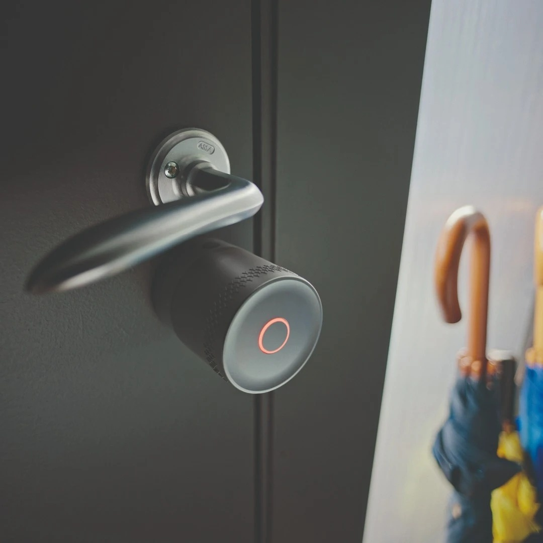 Ein moderner Türgriff mit einem runden, grauen Smart Lock mit rotem Licht.