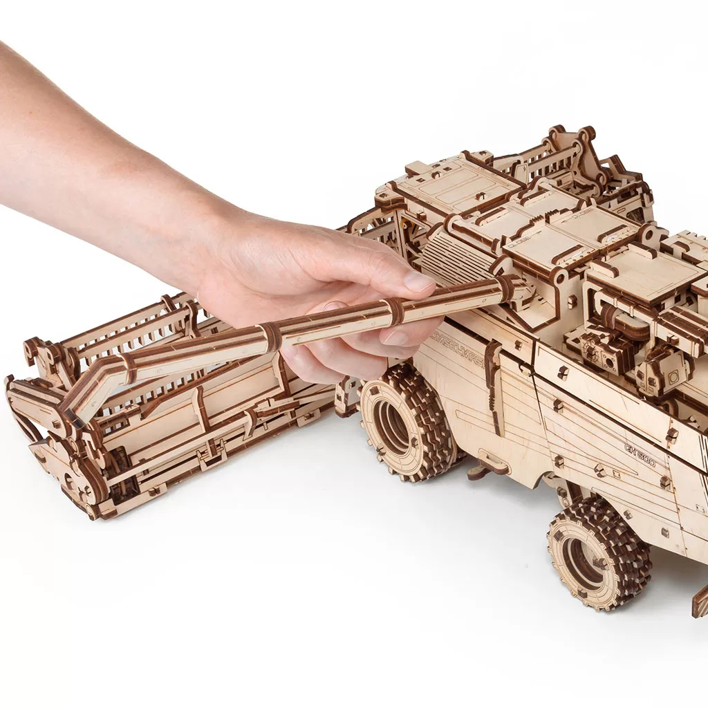 Eine Hand fügt ein Holzmodell eines Fahrzeugs zusammen.