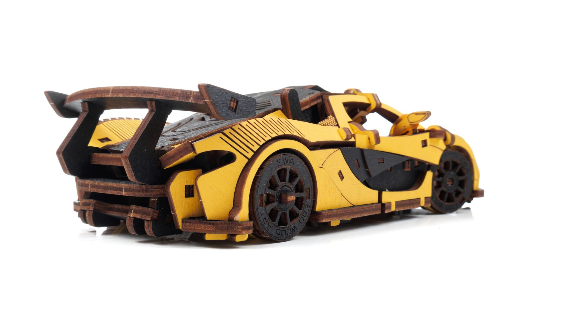 Ein gelbes Holzmodellauto mit schwarzem Spoiler und Rädern, auf weißem Hintergrund.