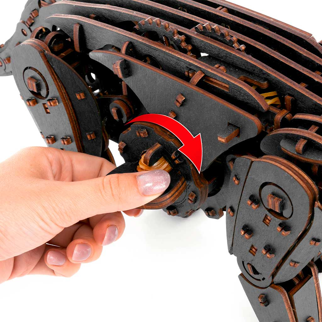 Eine Hand dreht ein Zahnrad an einem dunklen Holzmodell eines Tieres.