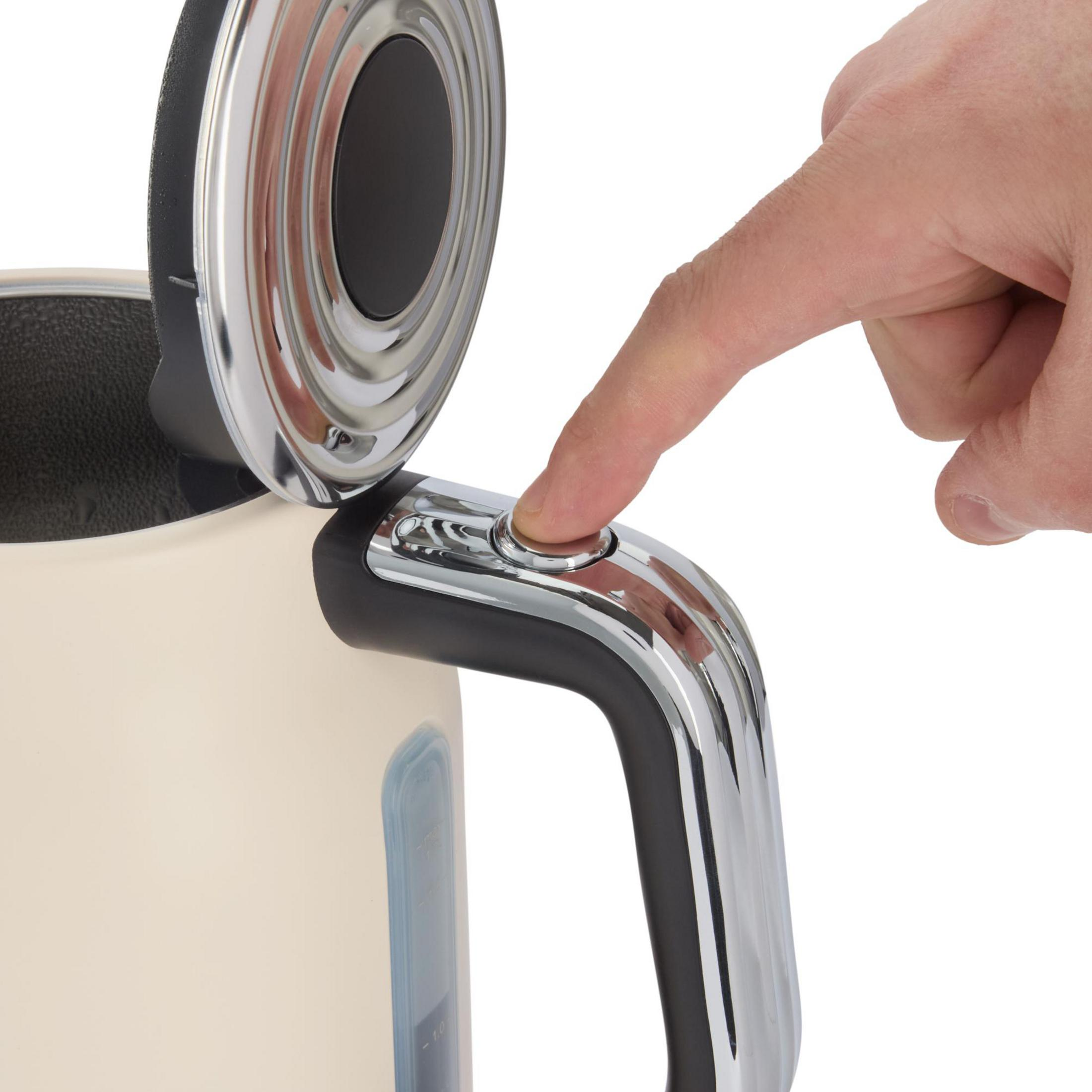 Ein Finger drückt auf einen Chromknopf an einem cremefarbenen Wasserkocher.