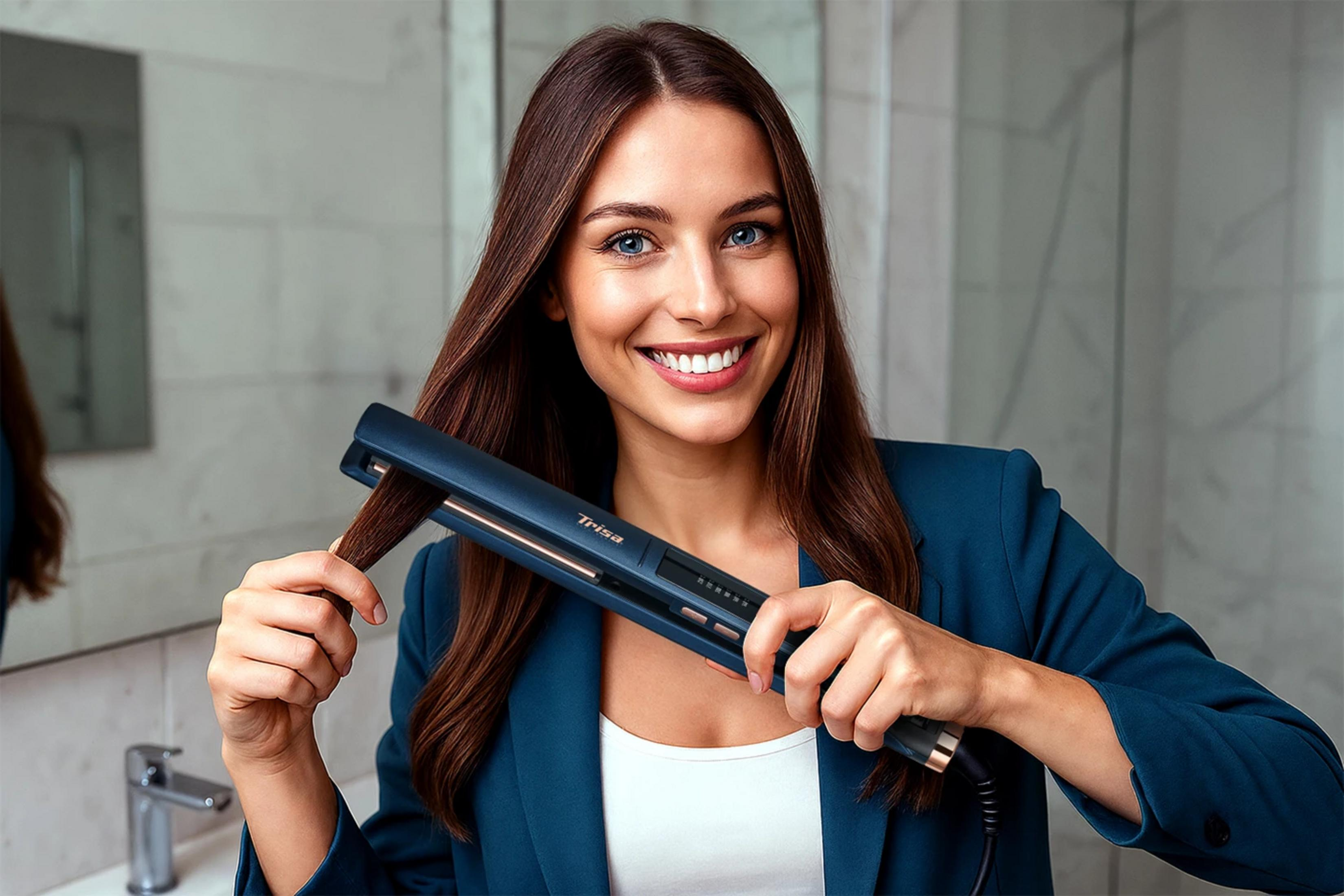 Una donna sorridente con capelli castani tiene una piastra scura, applicandola su una ciocca di capelli.