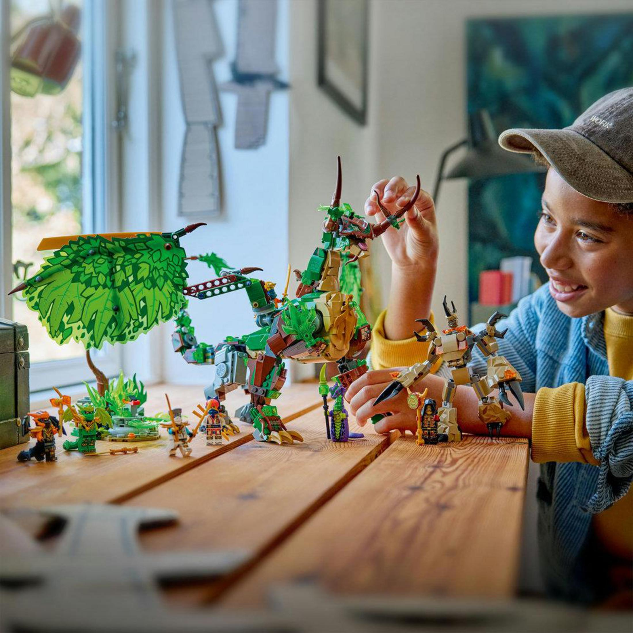 Chłopiec bawi się figurkami Lego, w tym zielonym smokiem i robotami.