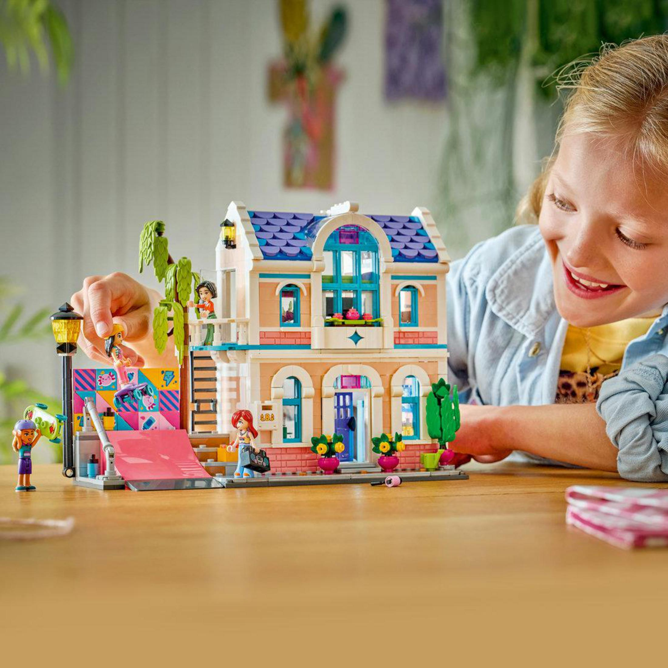 Una niña construye una casa de Lego colorida con figuras y un tobogán.