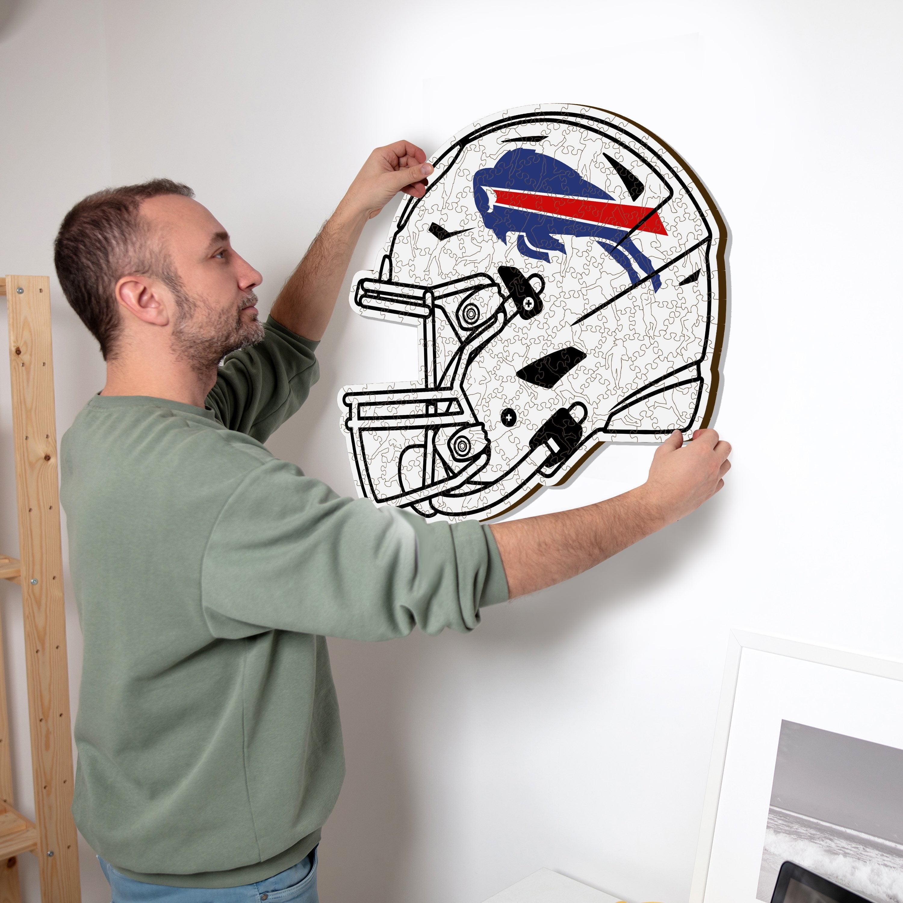 Ein Mann hängt ein Buffalo Bills Helm-Puzzle mit dem Logo an die Wand.