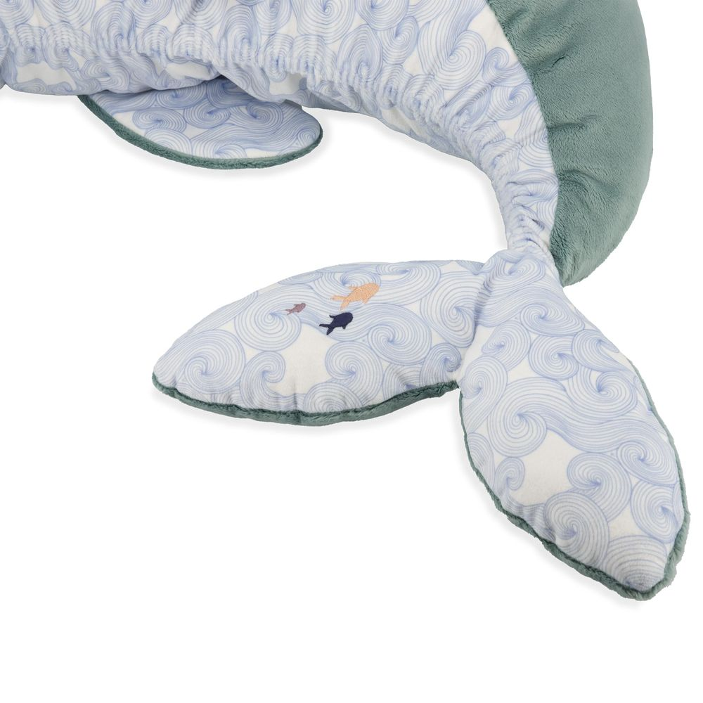 Una balena di peluche con motivo a onde blu e pinne verdi, con due pesciolini sulla coda.