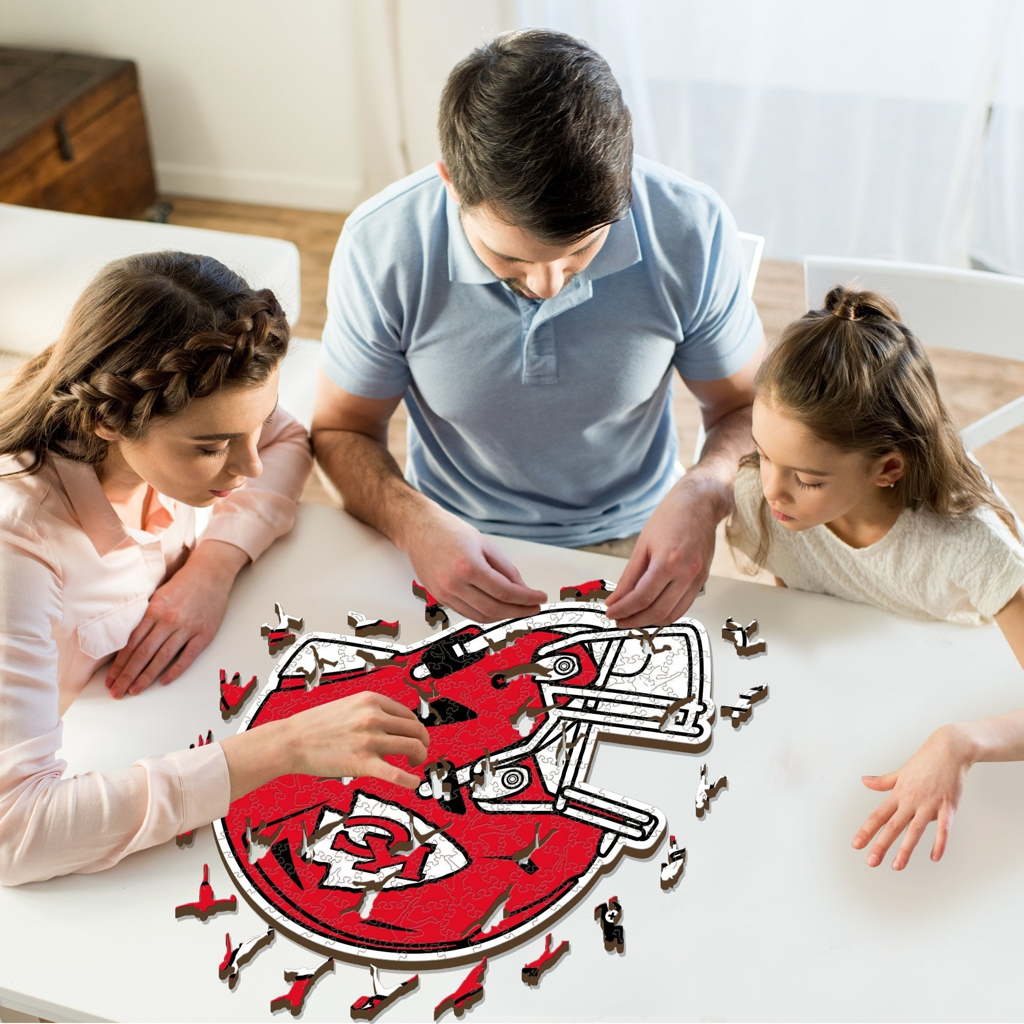 Familie puzzelt an einem roten Footballhelm-Puzzle.