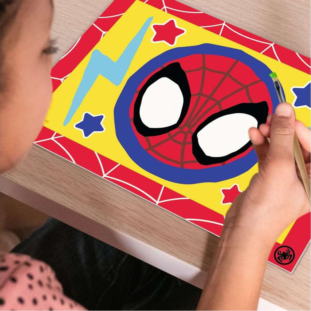 Un niño pinta ojos de Spiderman en un dibujo con estrellas y rayos.