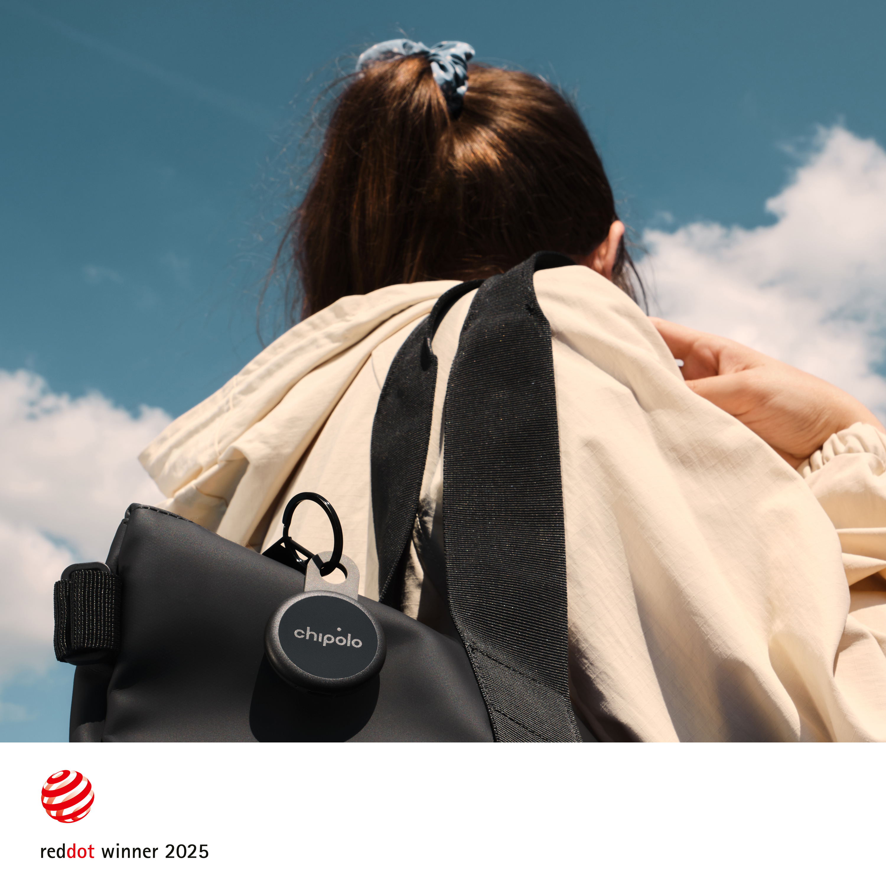 Une femme porte un sac avec un traqueur Chipolo sur fond de ciel bleu.