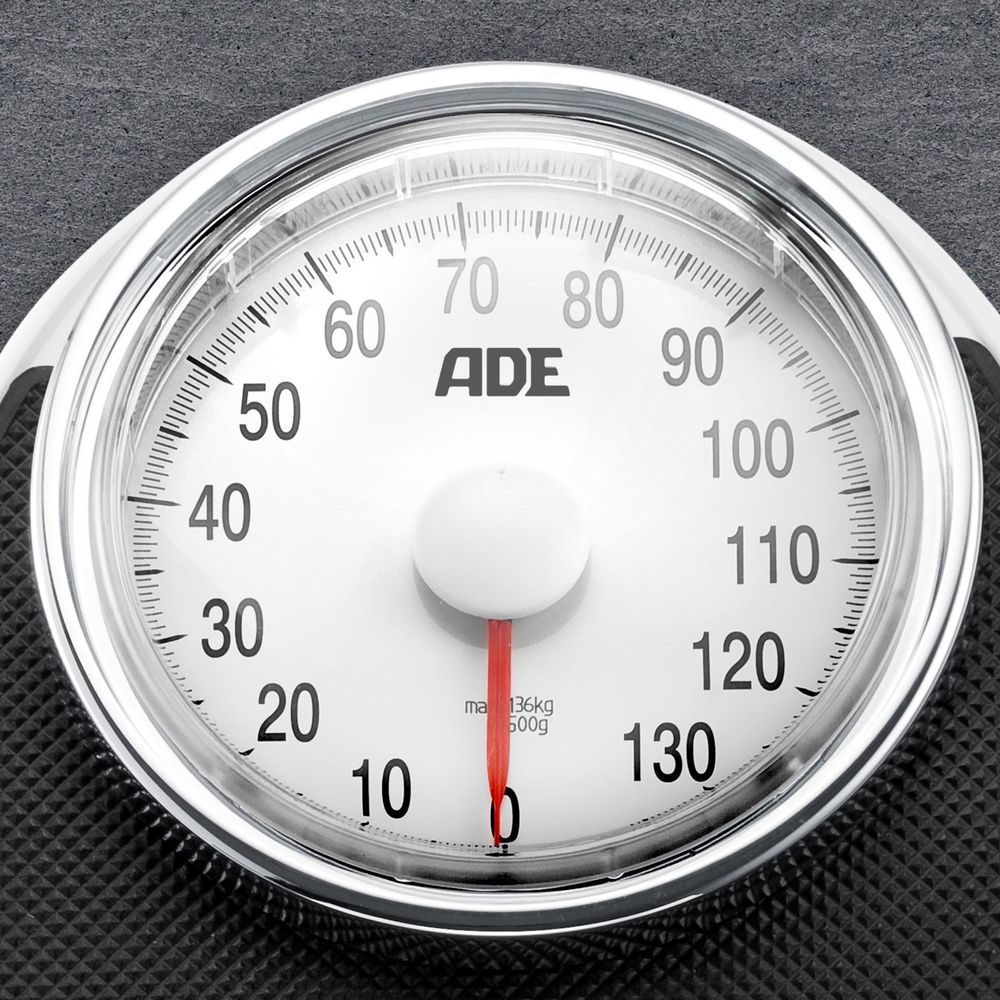 Waga z białą tarczą i srebrną ramką. Wskazówka jest na zerze.