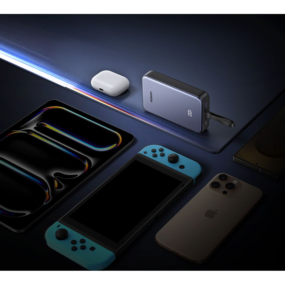 Powerbank, słuchawki, tablet, konsola i smartfony na ciemnej powierzchni.