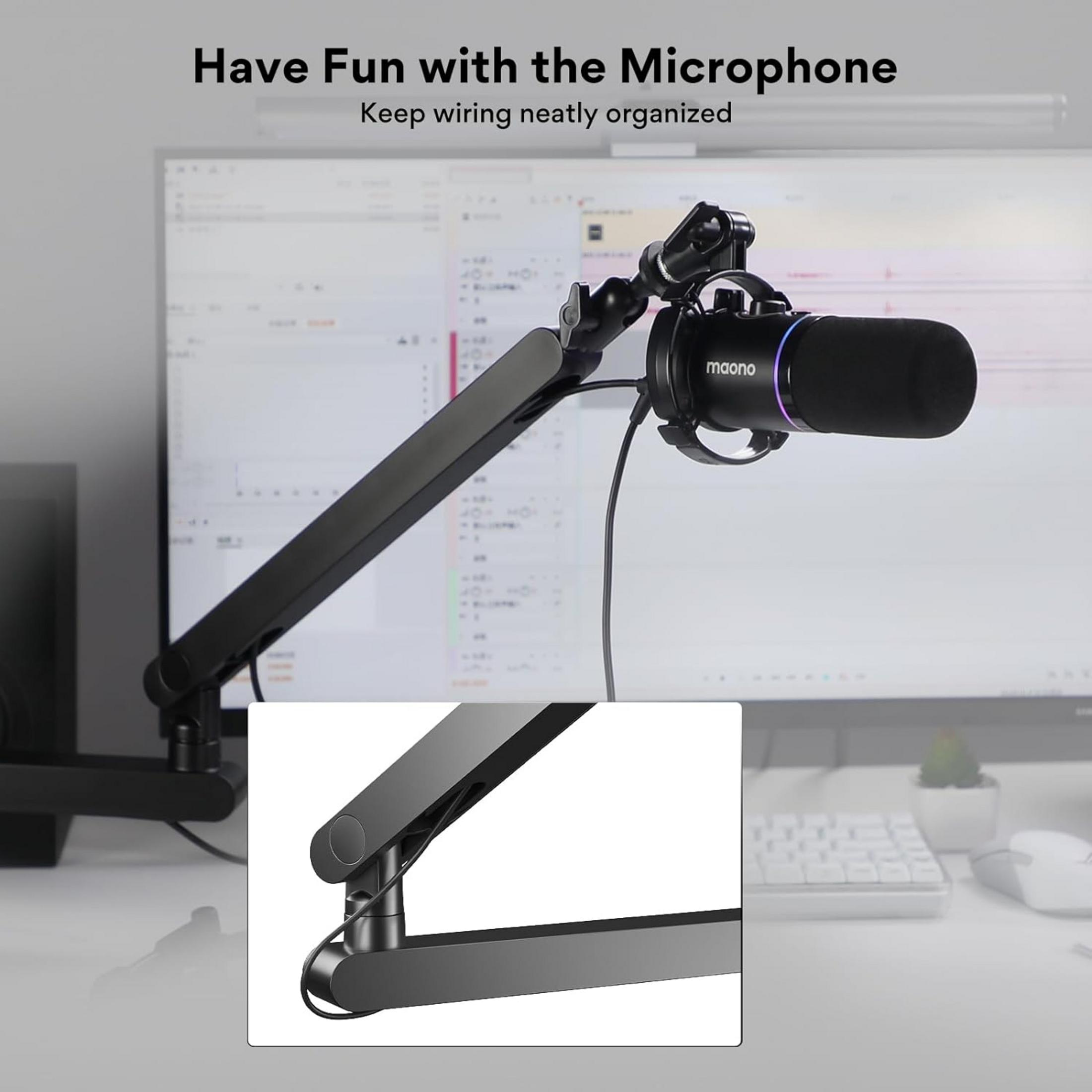 Un microfono nero su un braccio si libra sopra una scrivania con monitor.