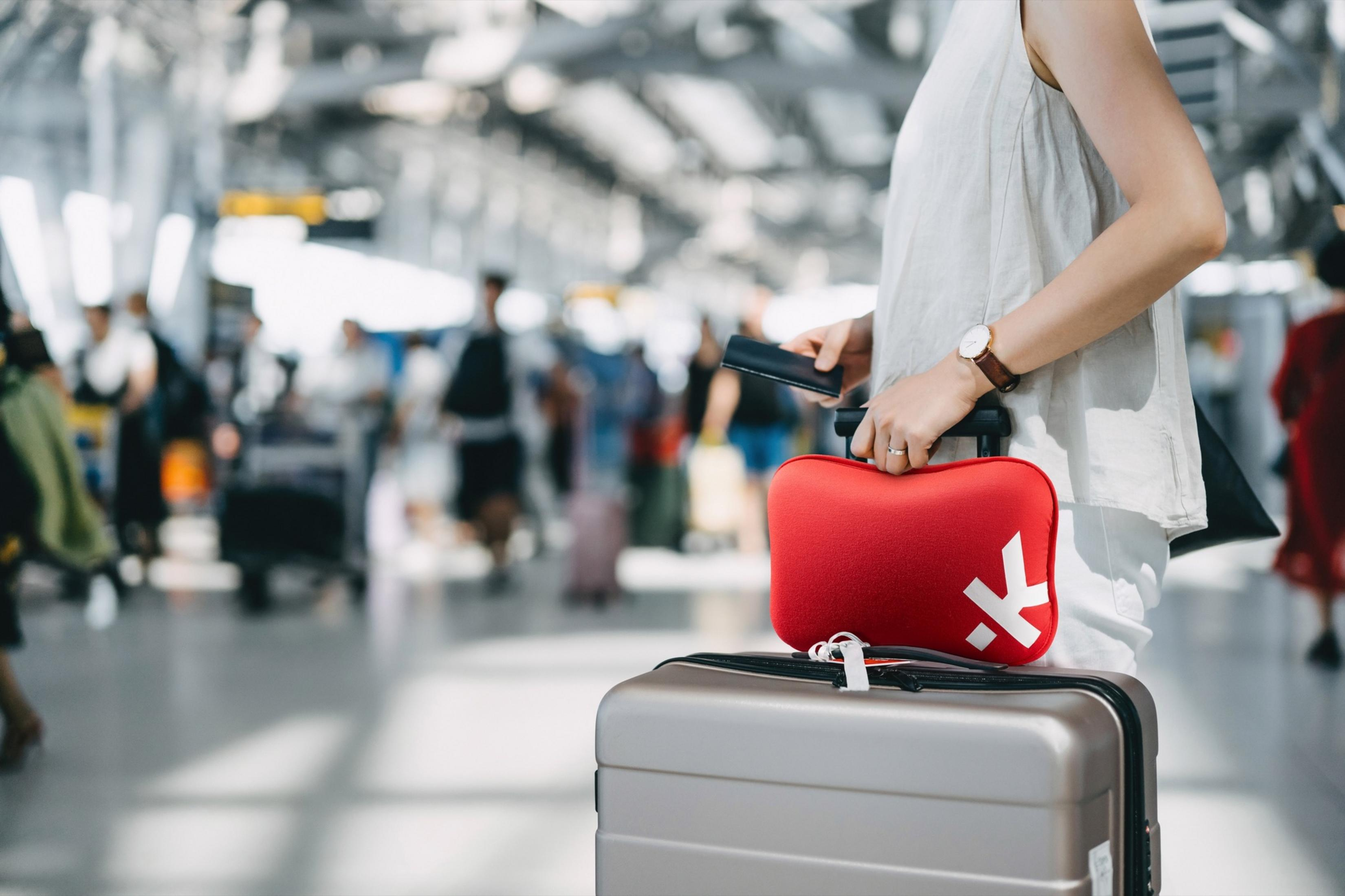 Personne avec valise et trousse de secours rouge à l'aéroport.