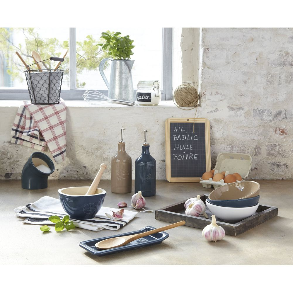 Utensili da cucina: mortaio, olierine, set di ciotole, uova e aglio su un tavolo.