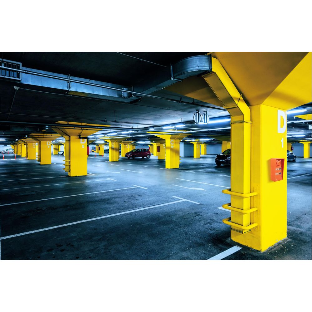 Ein leerer Parkplatz mit gelben Säulen und Autos. Blaue Beleuchtung.