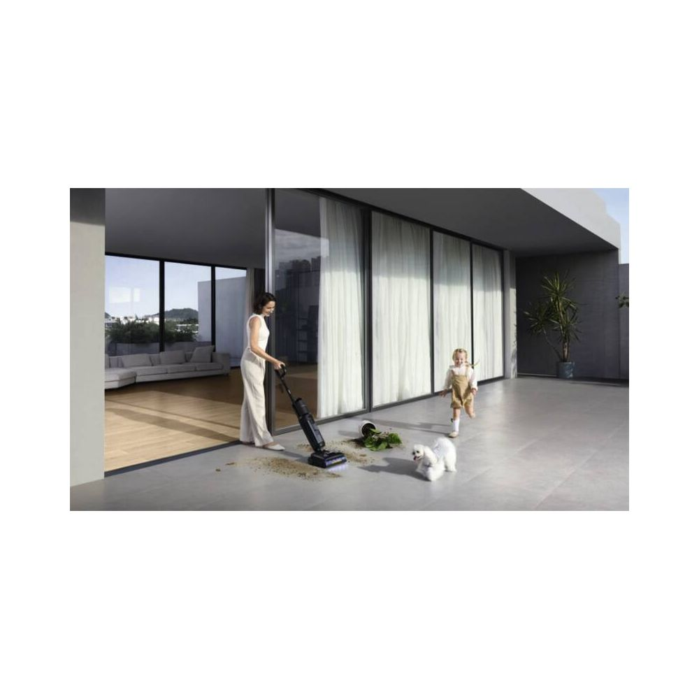 Kobieta odkurza podłogę, dziecko i pies przebiegają. Nowoczesny taras z przeszkleniem.